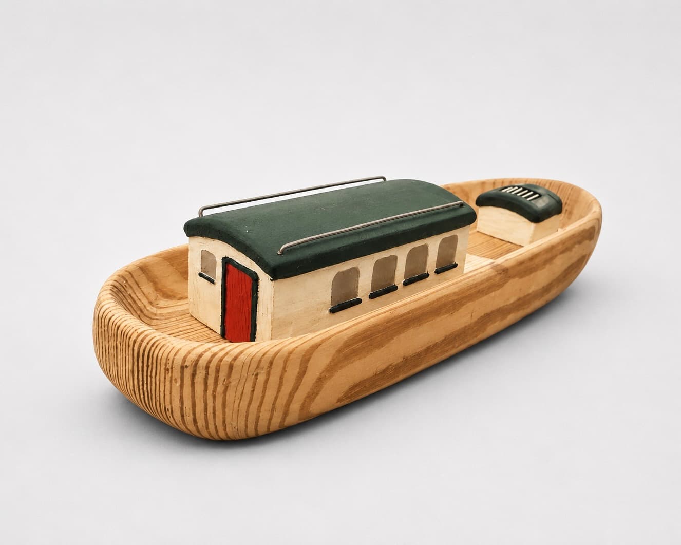 The boat early on: a plain carved wooden hull with a simple green and white deckhouse
